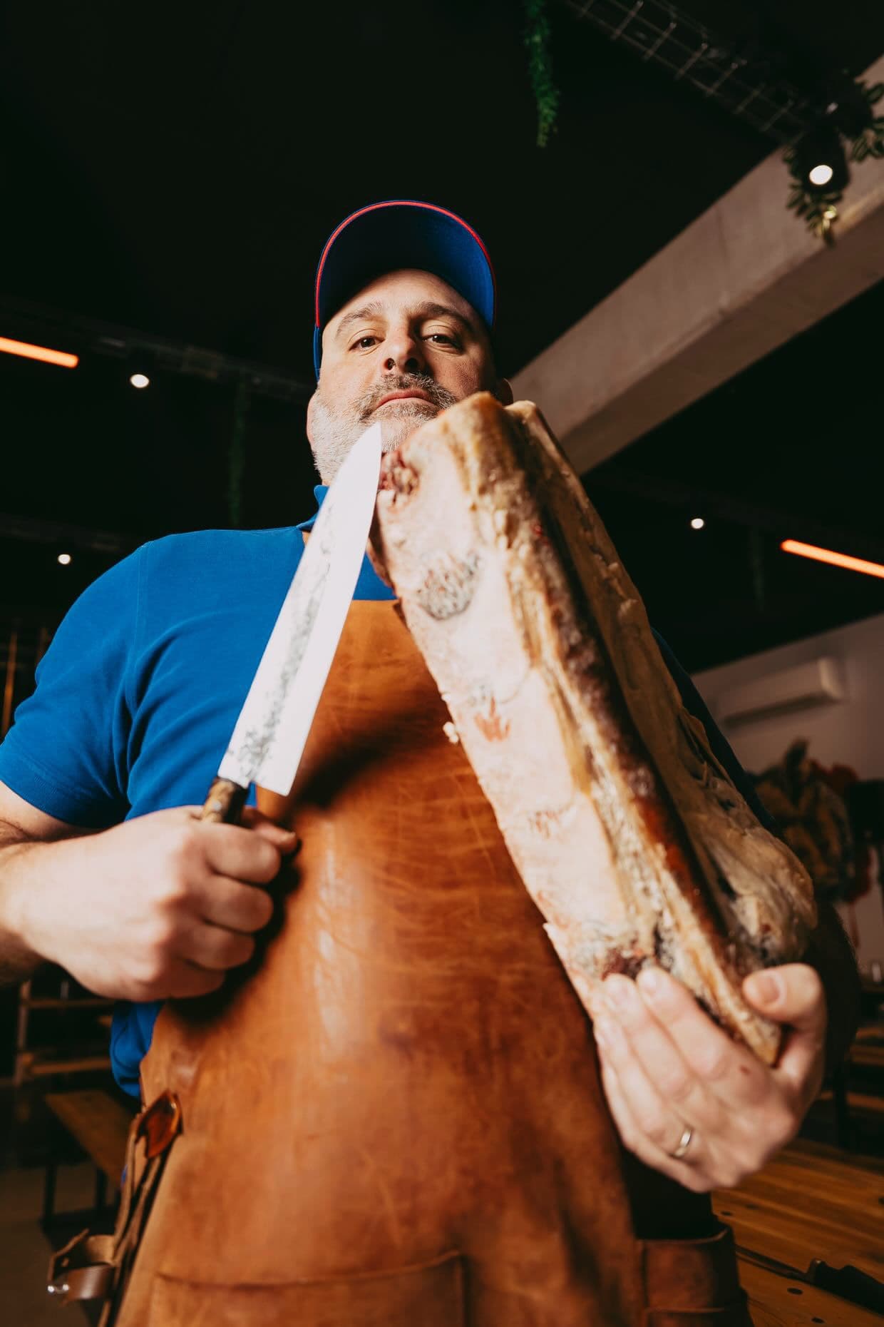Floréal en contre-plongée tenant une côte de bœuf maturée et un grand couteau